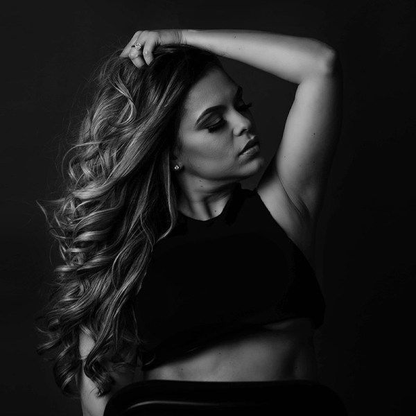 A woman with long hair is holding her hair in a black and white photo.