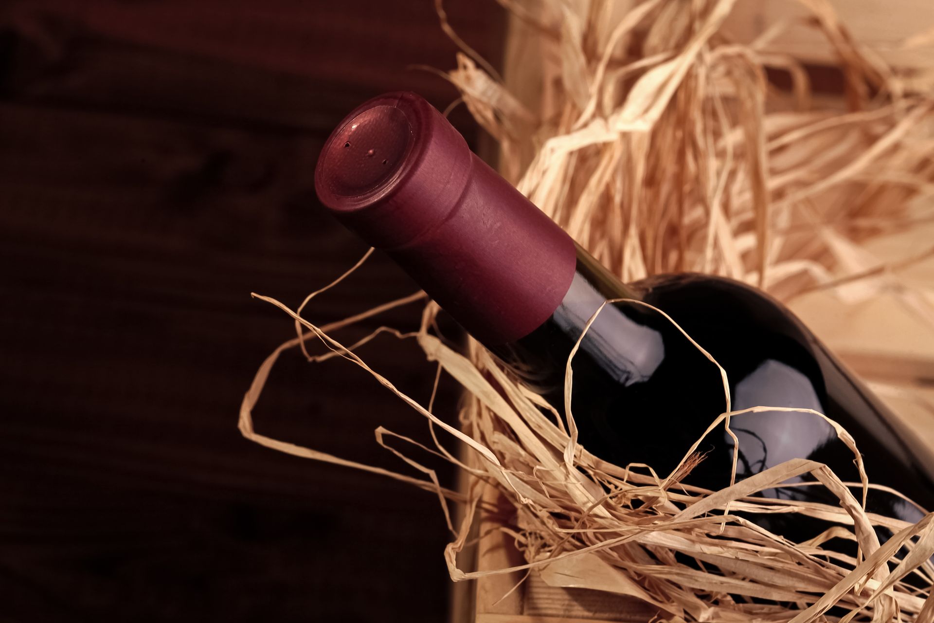 One luxury full dark glass bottle of red expensive collection grape wine in gift wooden box with straw, horizontal photo.