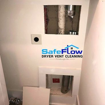 A white wall with a hole in it and a safe flow dryer vent cleaning logo on it.