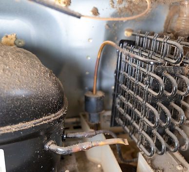 A close up of a refrigerator compressor and condenser