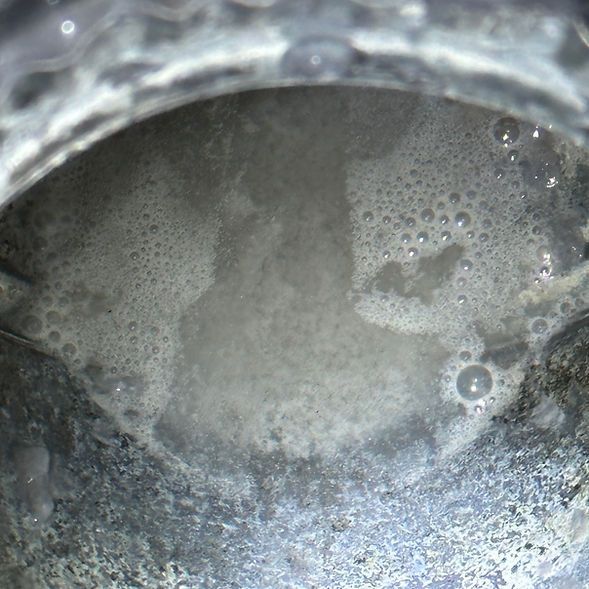 A close up of a pot of water with bubbles coming out of it.