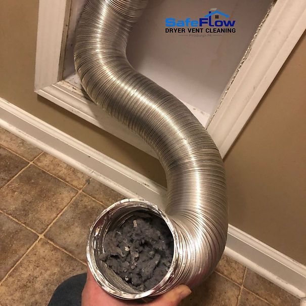 A person is holding a dirty dryer vent hose in their hand.