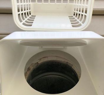 A white trash can with the lid open and a hole in the middle