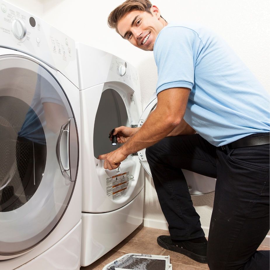 A man in a blue shirt is working on a washing machine