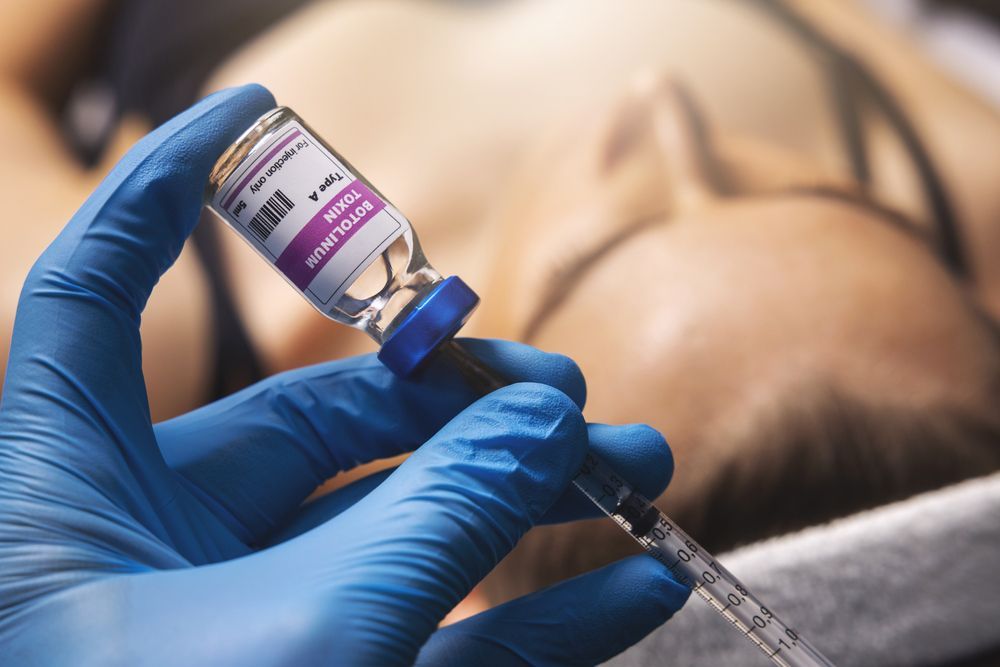 A person is holding a bottle of vaccine and a syringe in front of a woman.
