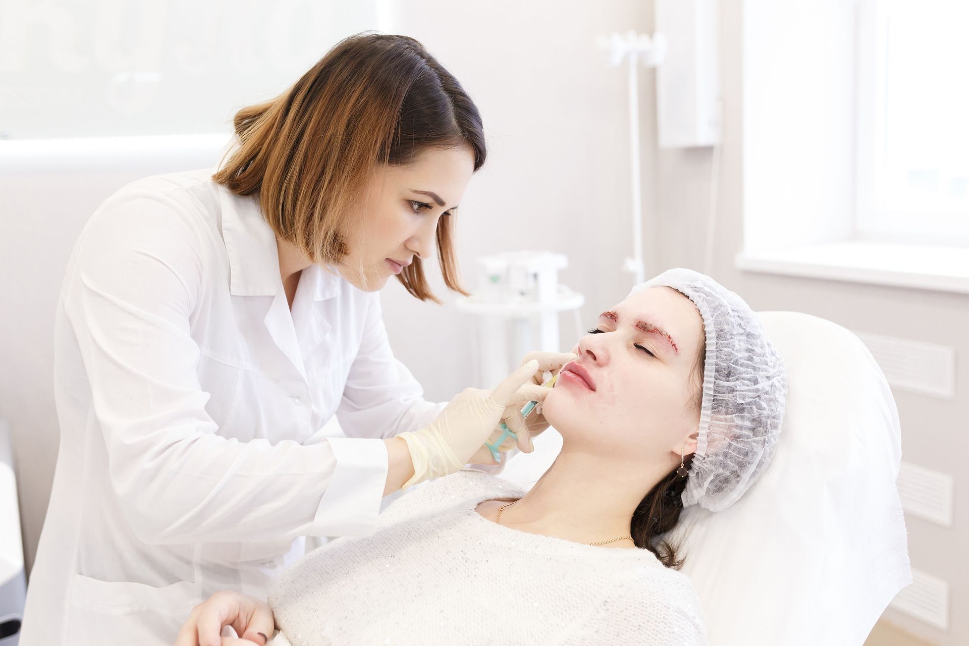 A woman is laying on a bed while a doctor examines her face.