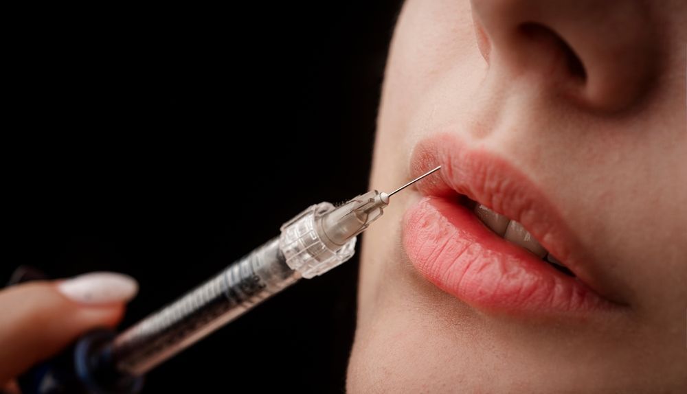 A woman is getting a botox injection in her lips.