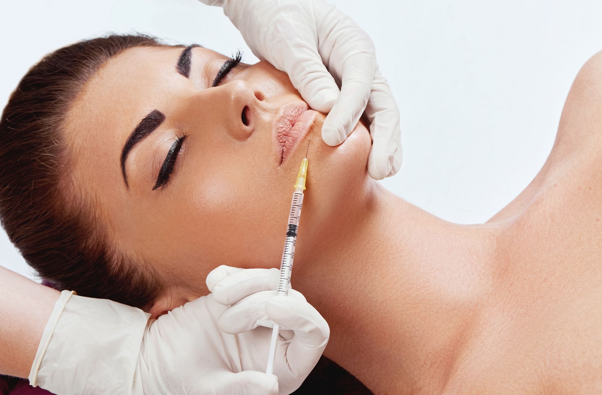 A woman is getting a botox injection in her lips.