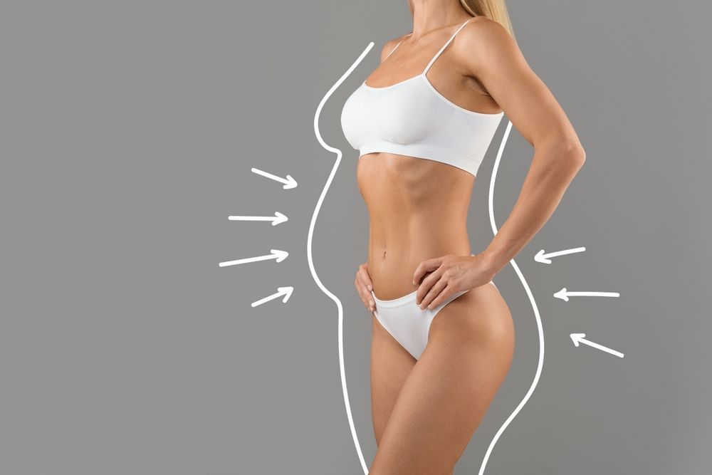 A woman in white underwear is standing with her hands on her hips on a gray background.