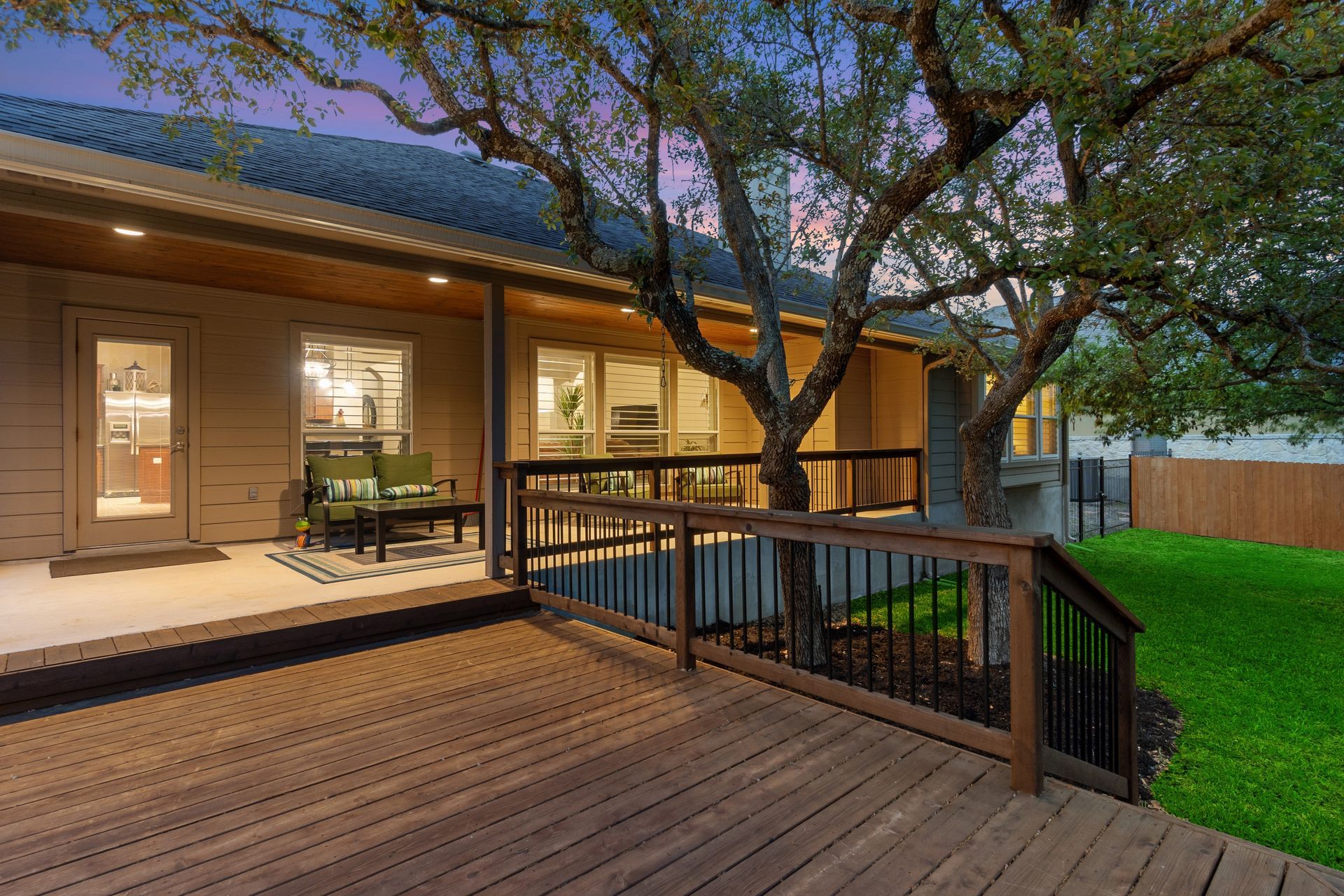 The backyard of a house with a large wooden deck and a tree.