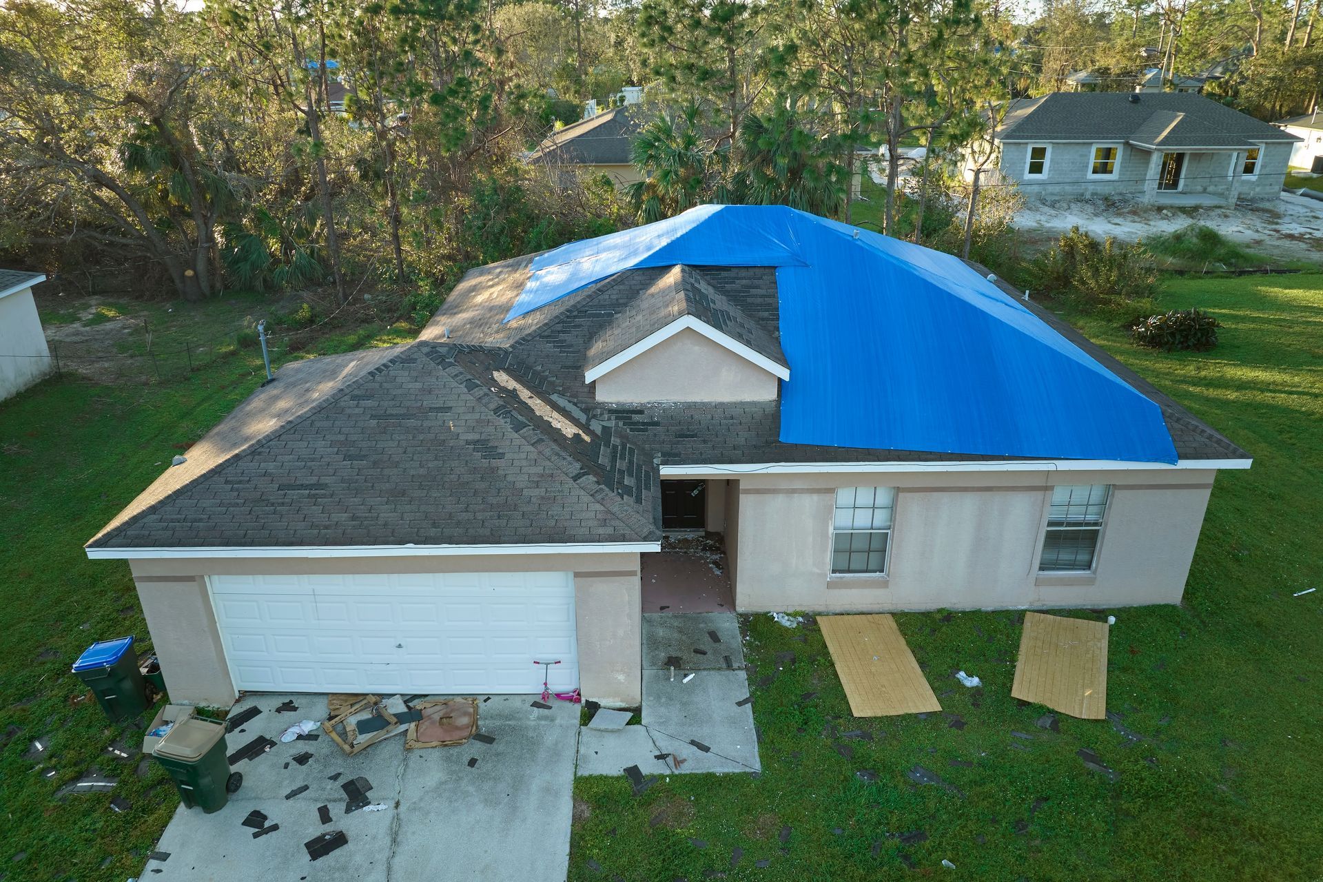 An aerial view of a house with a blue tarp on the roof.