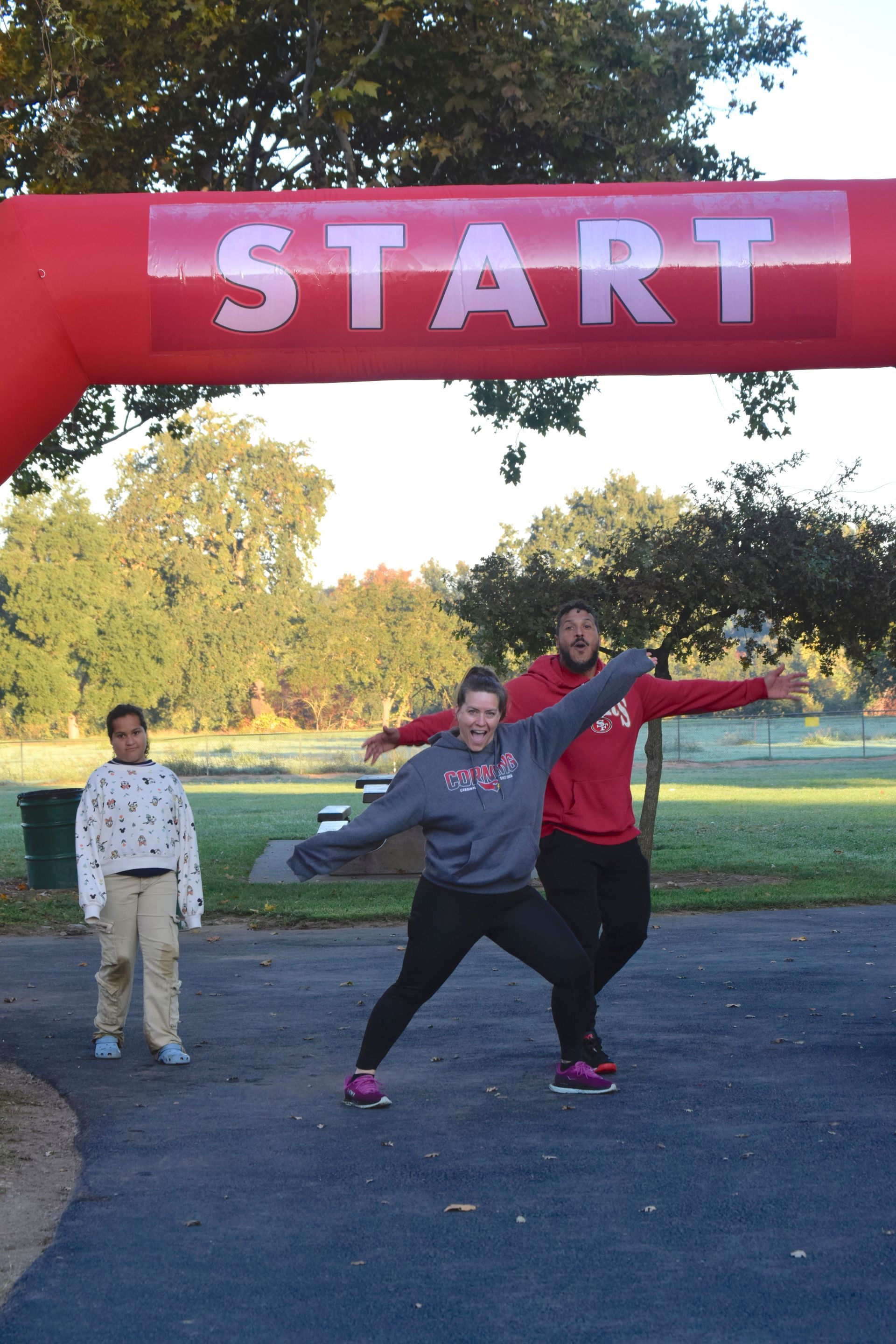 People at a race starting line. Two people in athletic wear strike poses under the 