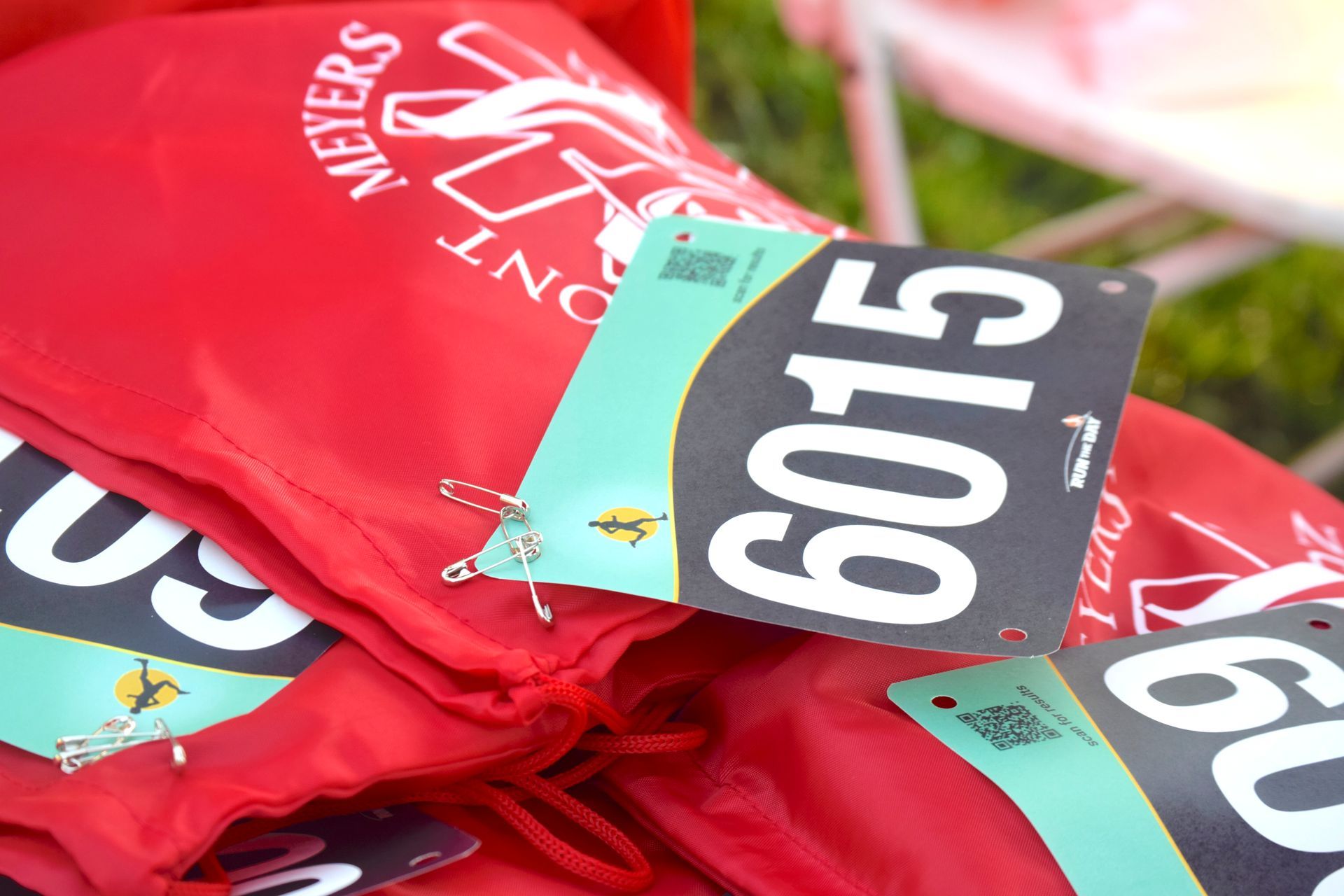 Red drawstring bags with bib numbers 6015 attached by safety pins.