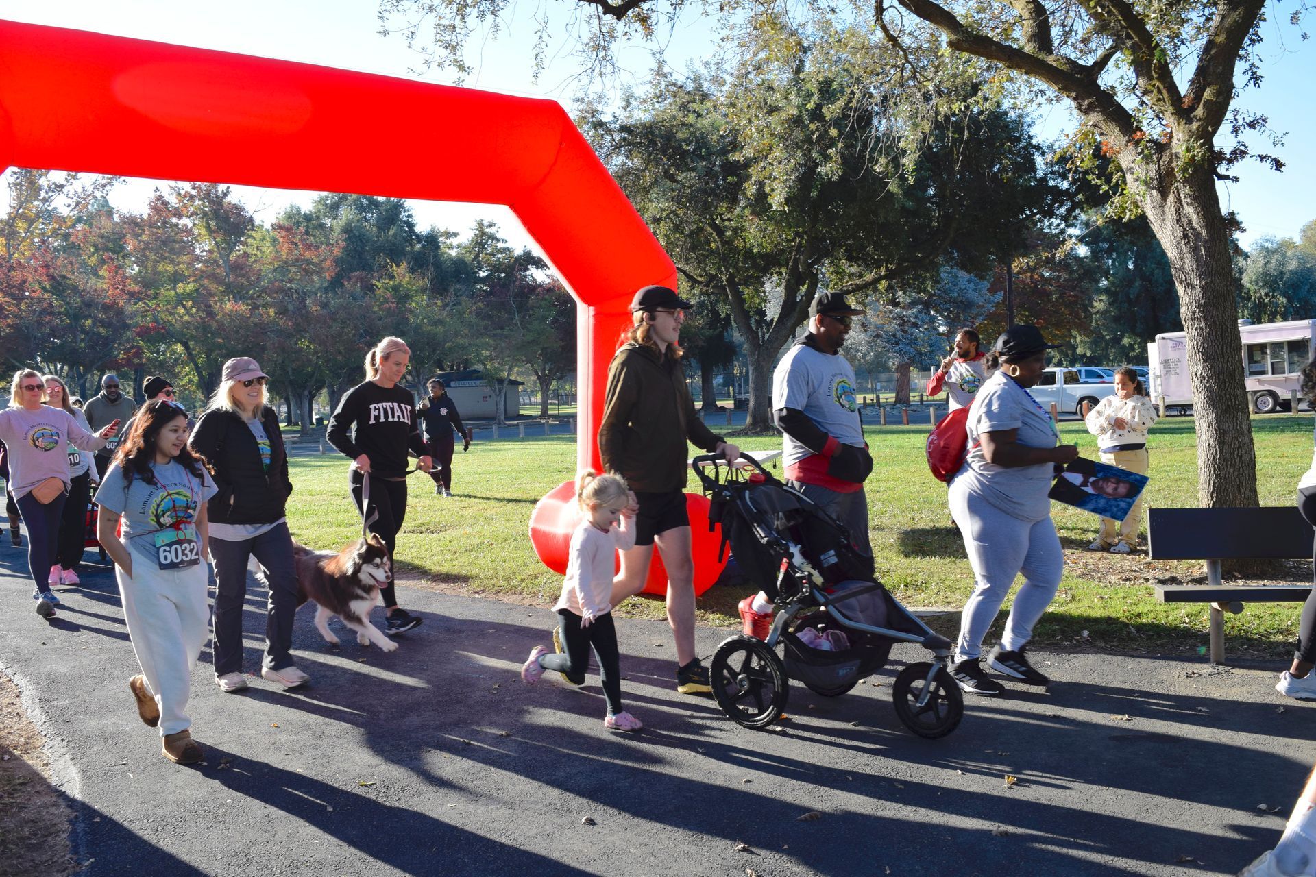 People walking under a red arch, likely at a park for a walk/run event.