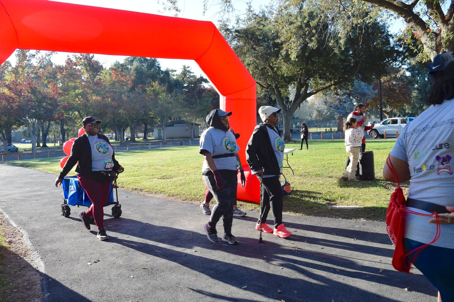People walking/running under an orange inflatable arch at an outdoor event.