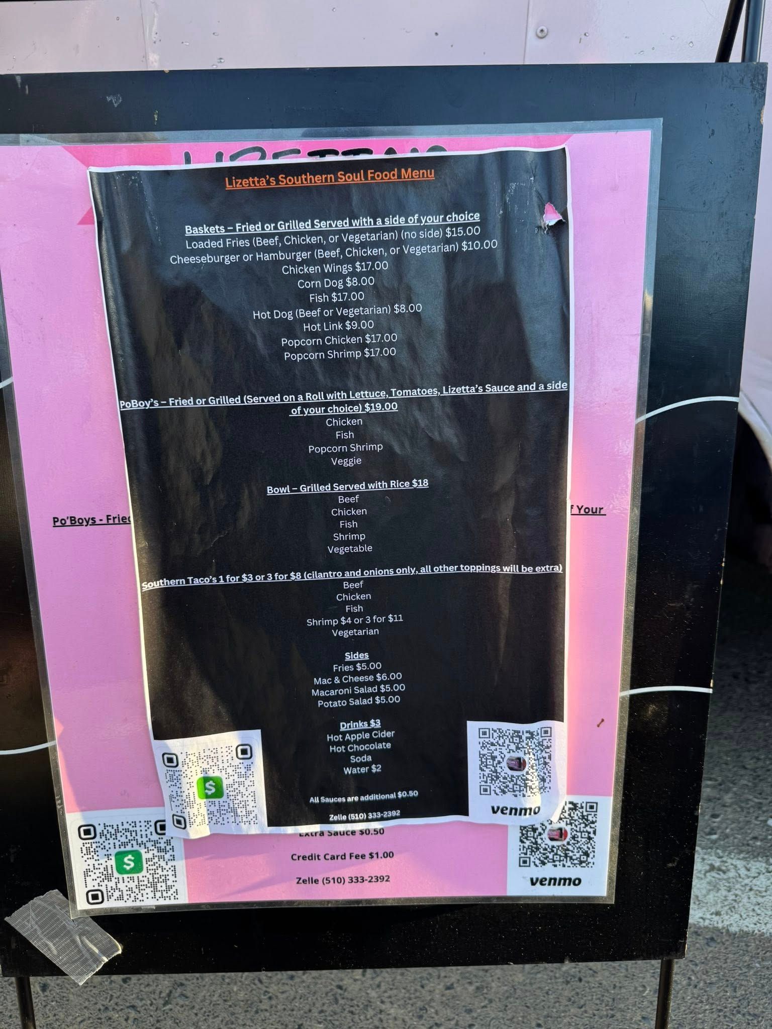 Black poster with white text, pink border, and QR codes; attached to a black board.