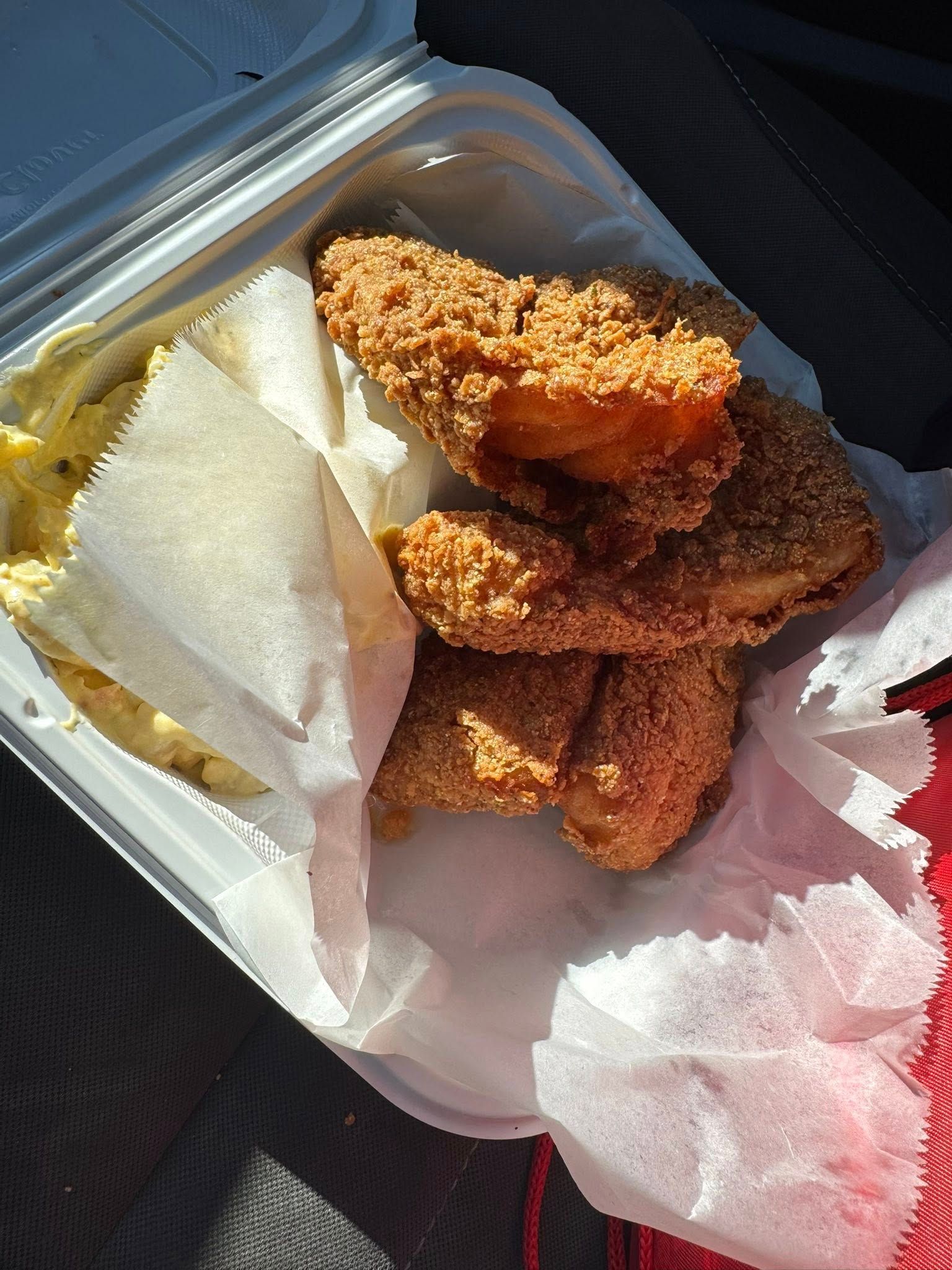Fried chicken tenders and macaroni and cheese in a takeout container.