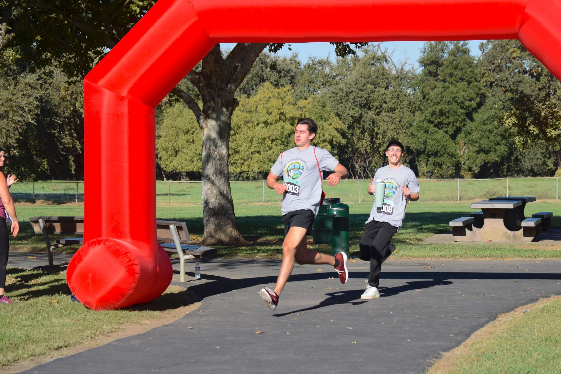 Two runners near a red arch at a park, running.