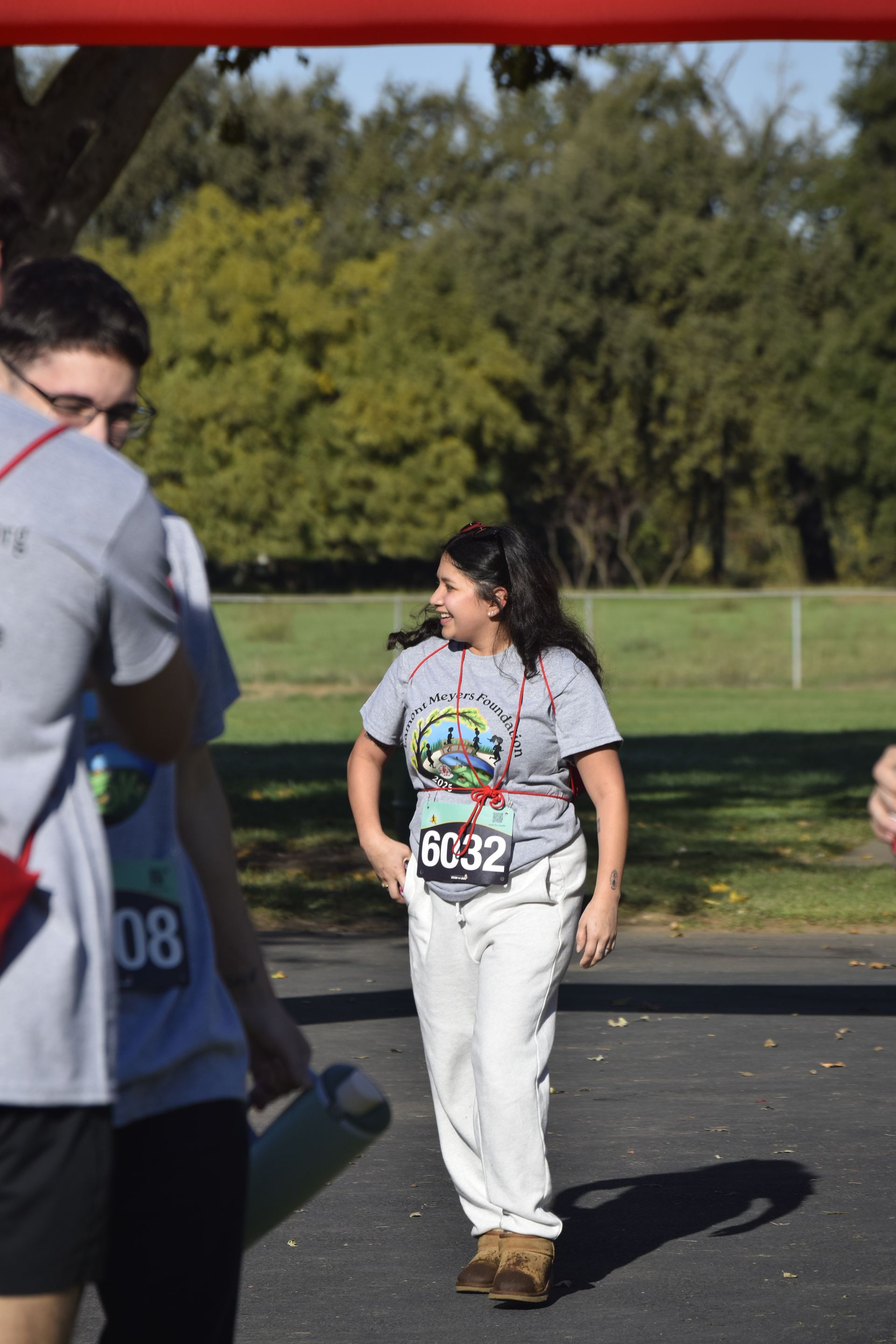 Person in a race, with bib number 6032, smiling as they cross a finish line.