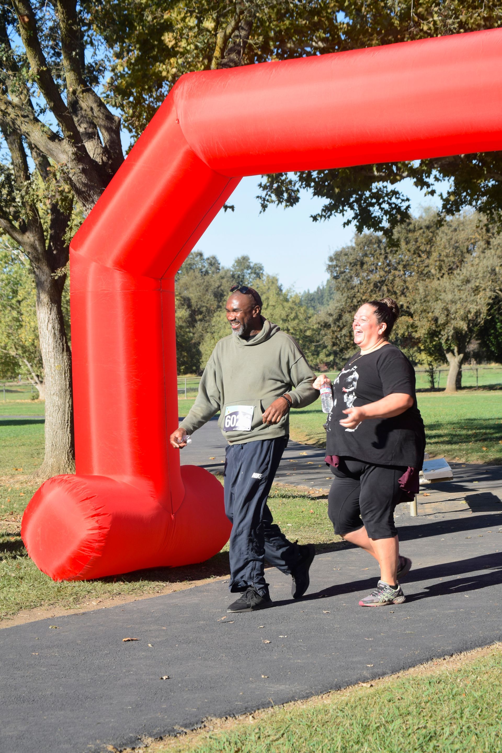 Two people running under a red inflatable arch at an outdoor event.