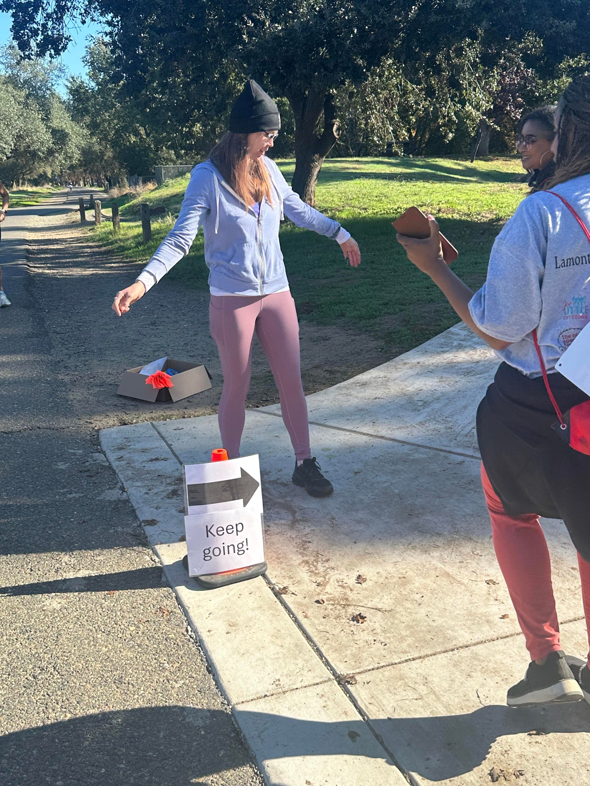 Woman balancing, looking at a person holding a phone. 
