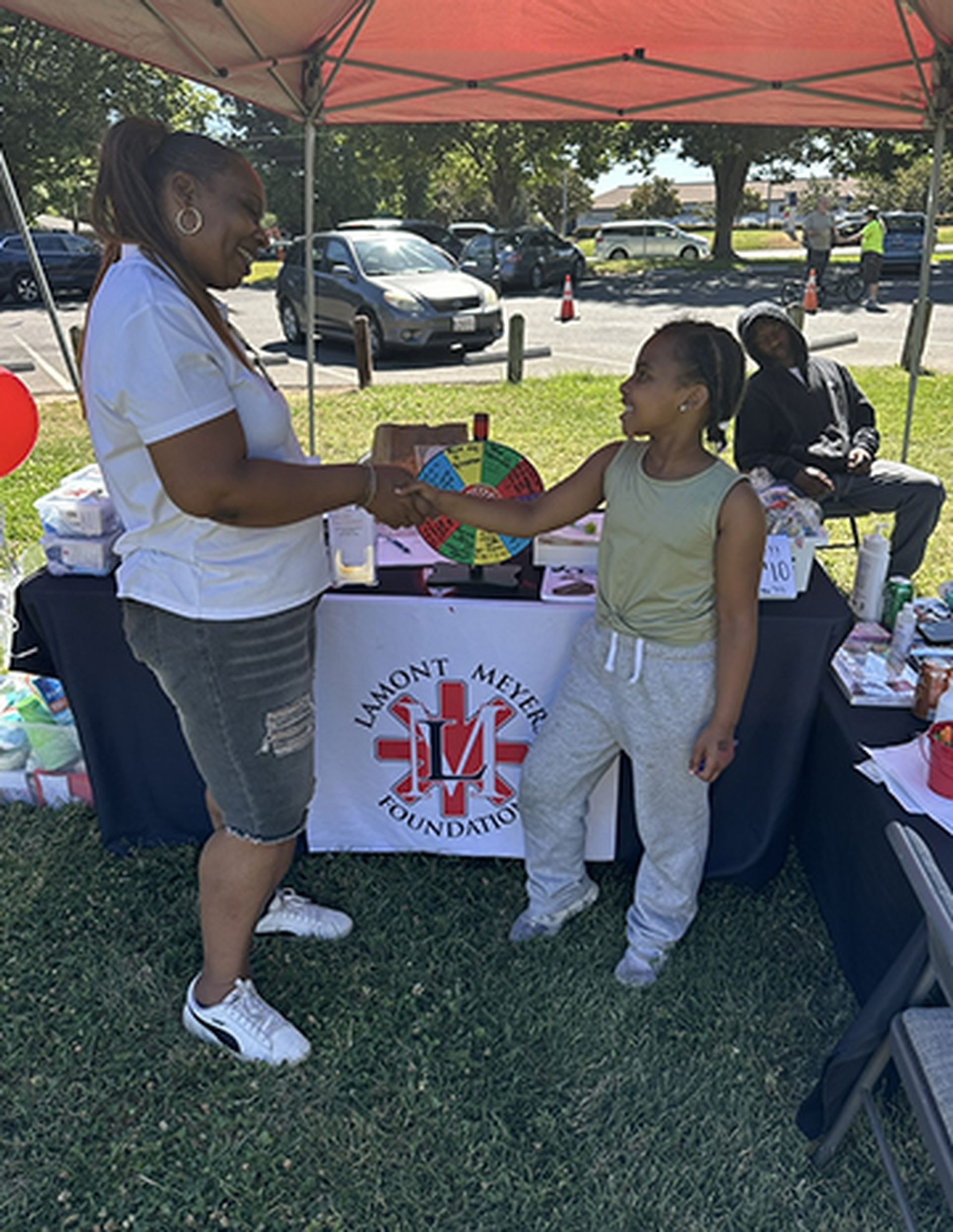 A woman and a little girl are standing in front of a table.