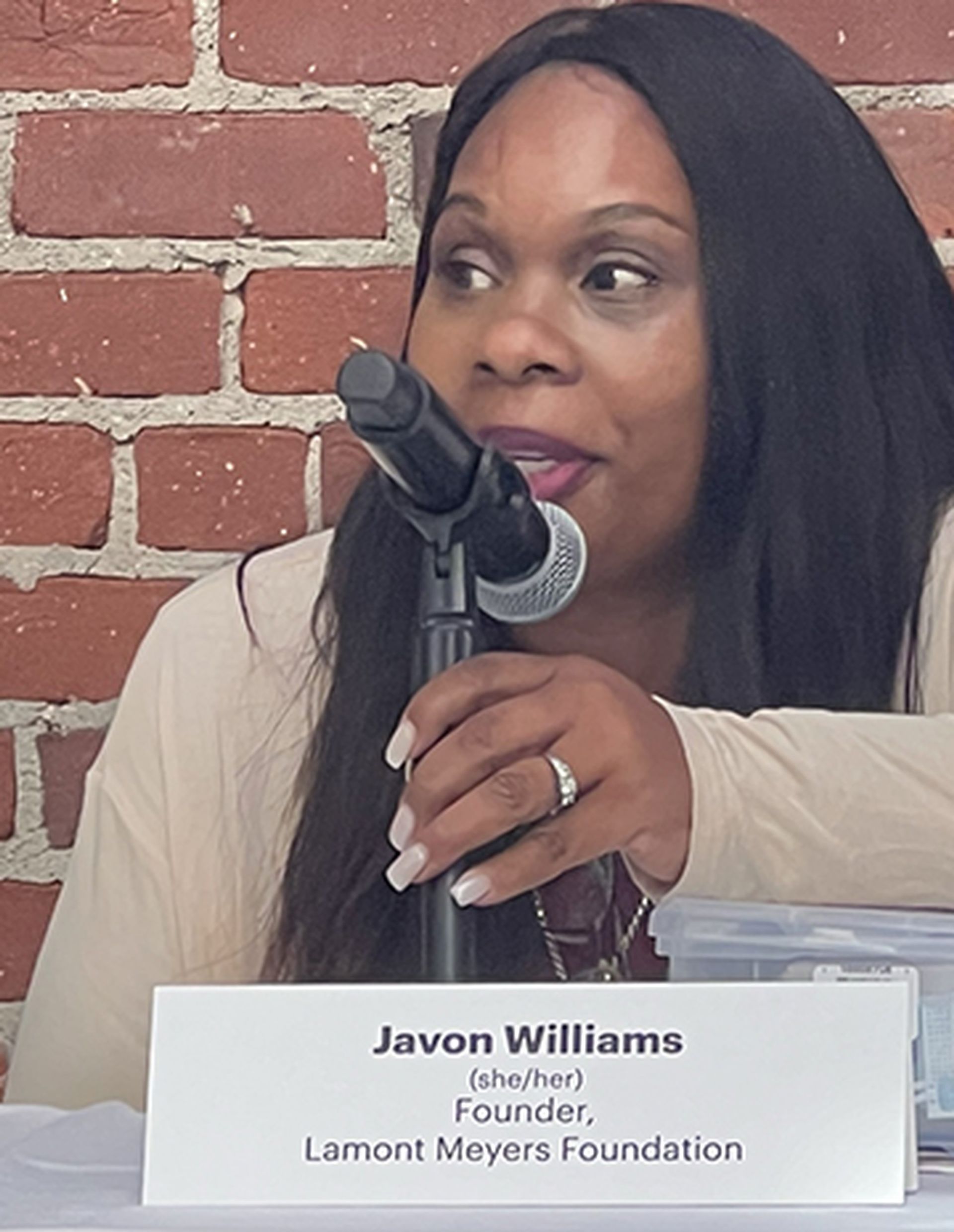 A woman sitting at a table with a sign that says javon williams