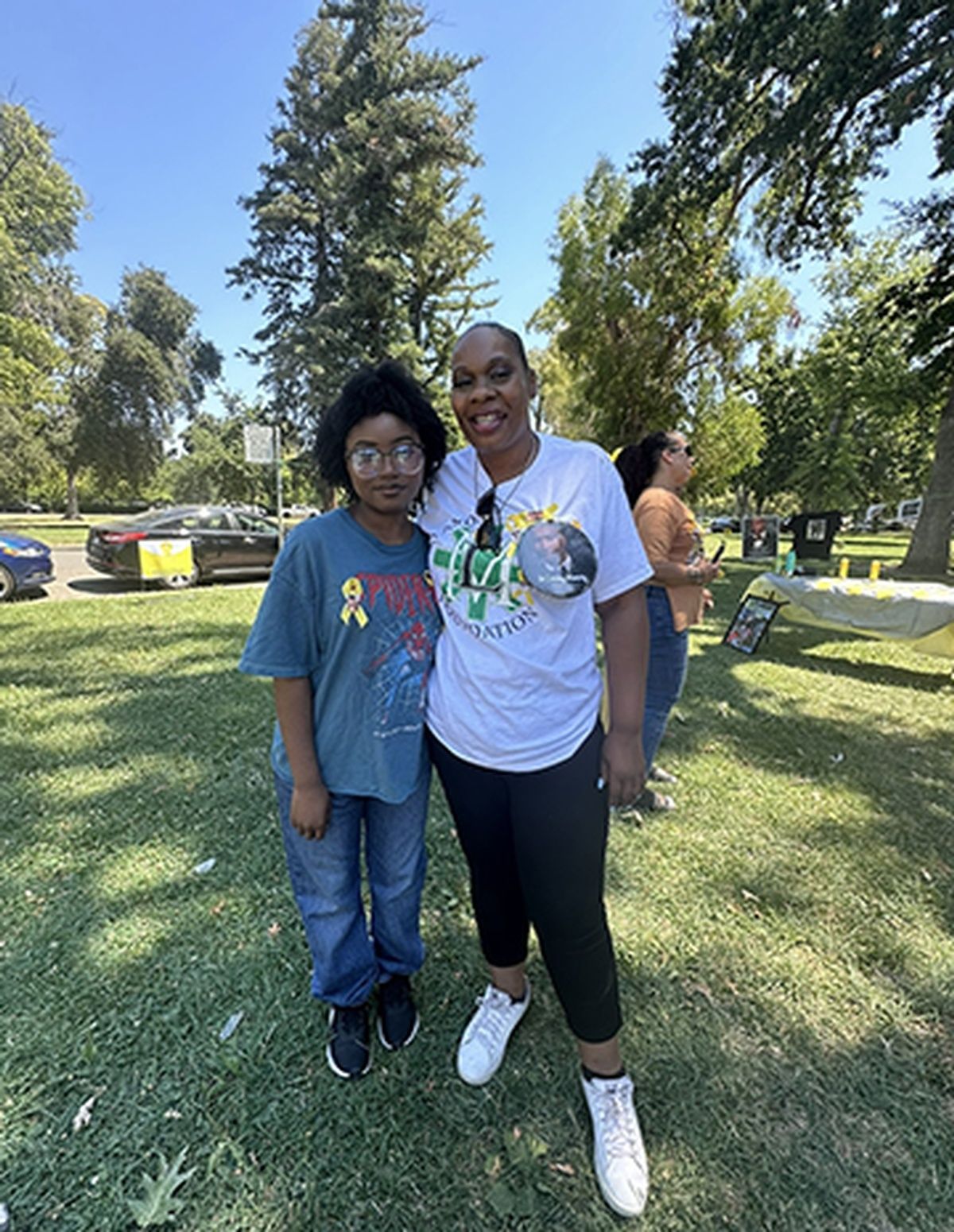 A woman and a boy are posing for a picture in a park.