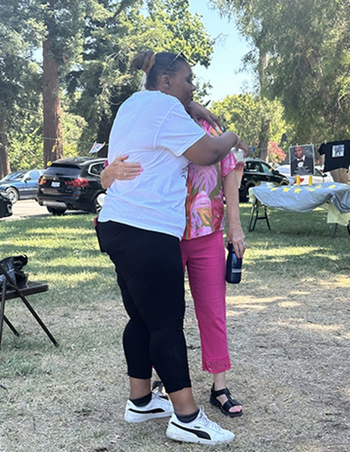 Two women are hugging each other in a park.