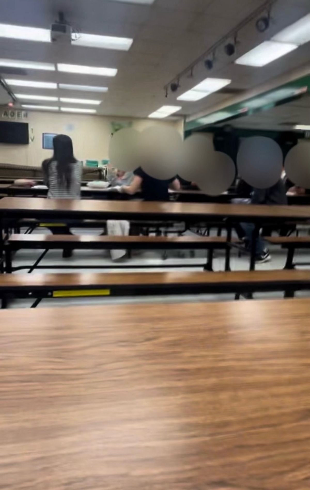 A woman sits at a table in a school cafeteria