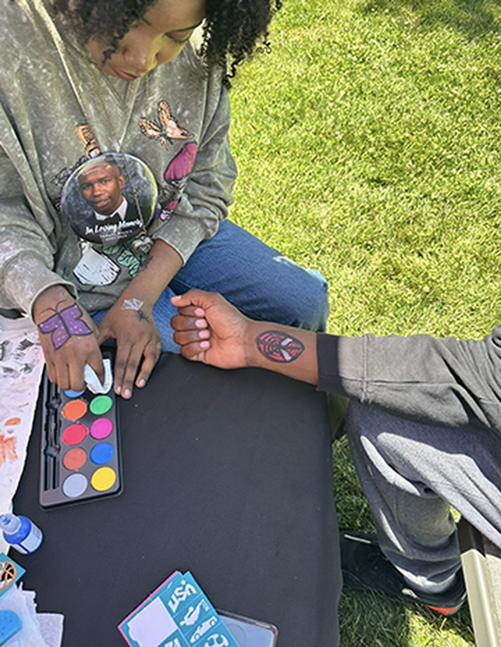 A woman is getting a tattoo on a man 's wrist.