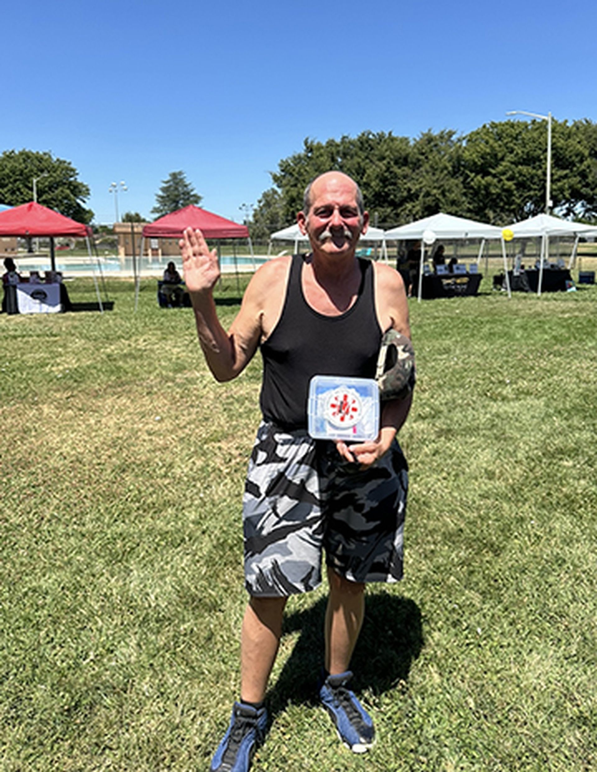 A man is standing in a grassy field holding a sign.