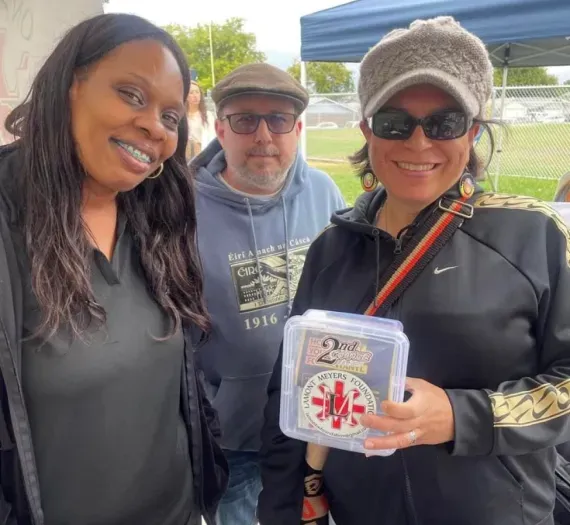 A group of people are posing for a picture and one woman is holding a box that says 2nd place