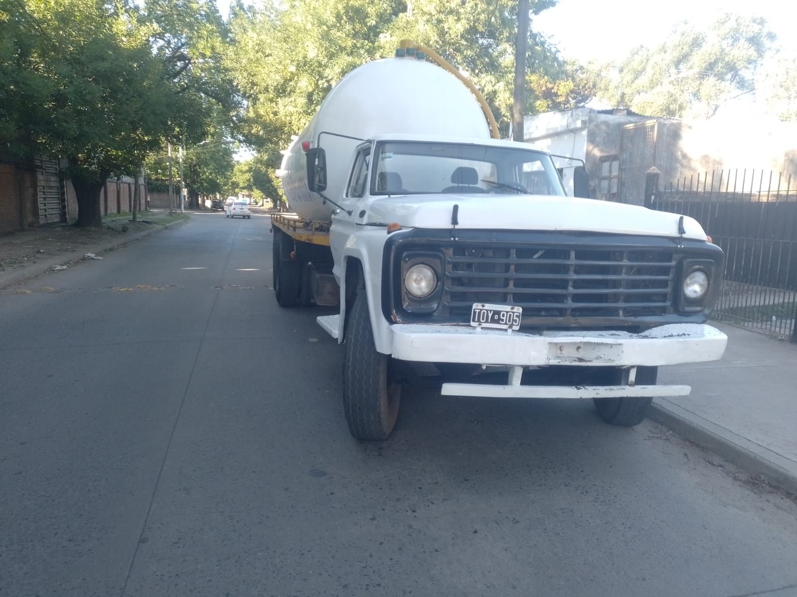 Camión blanco con tanque grande y redondo estacionado en una calle.