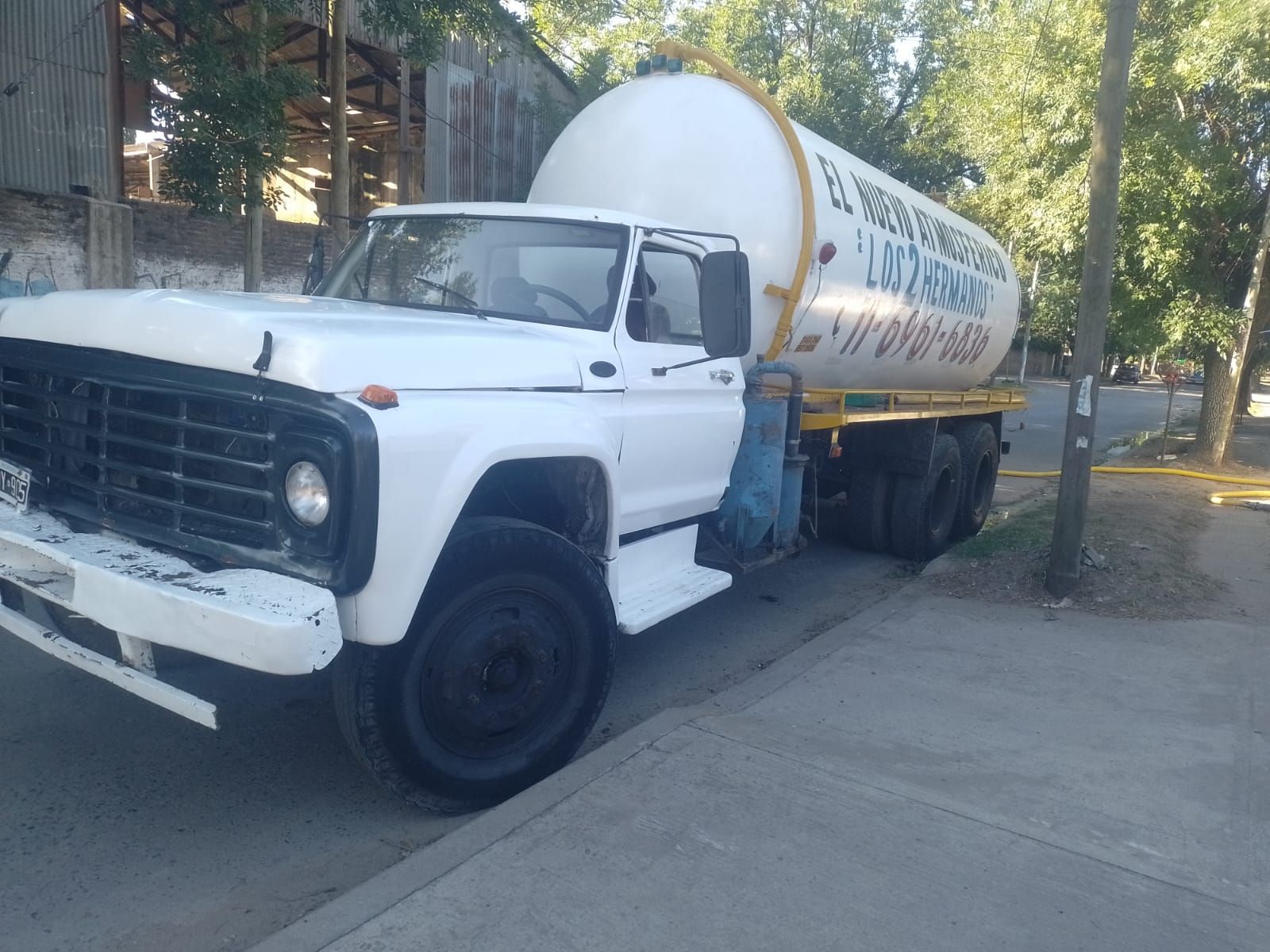 Camión cisterna blanco estacionado en una calle; una persona está parada cerca de la cabina.