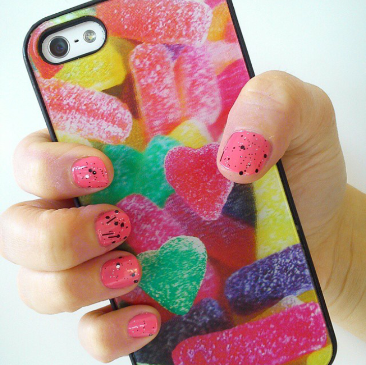 Una persona con uñas rosas sostiene un teléfono celular con ositos de goma.