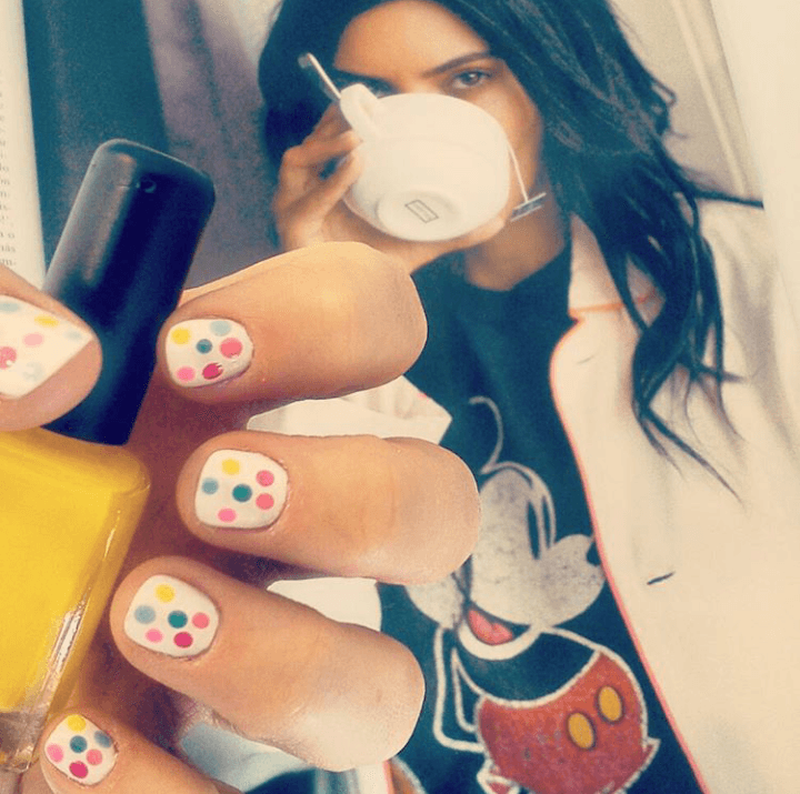 Una mujer que lleva una camiseta de Mickey Mouse sostiene una botella de esmalte de uñas.