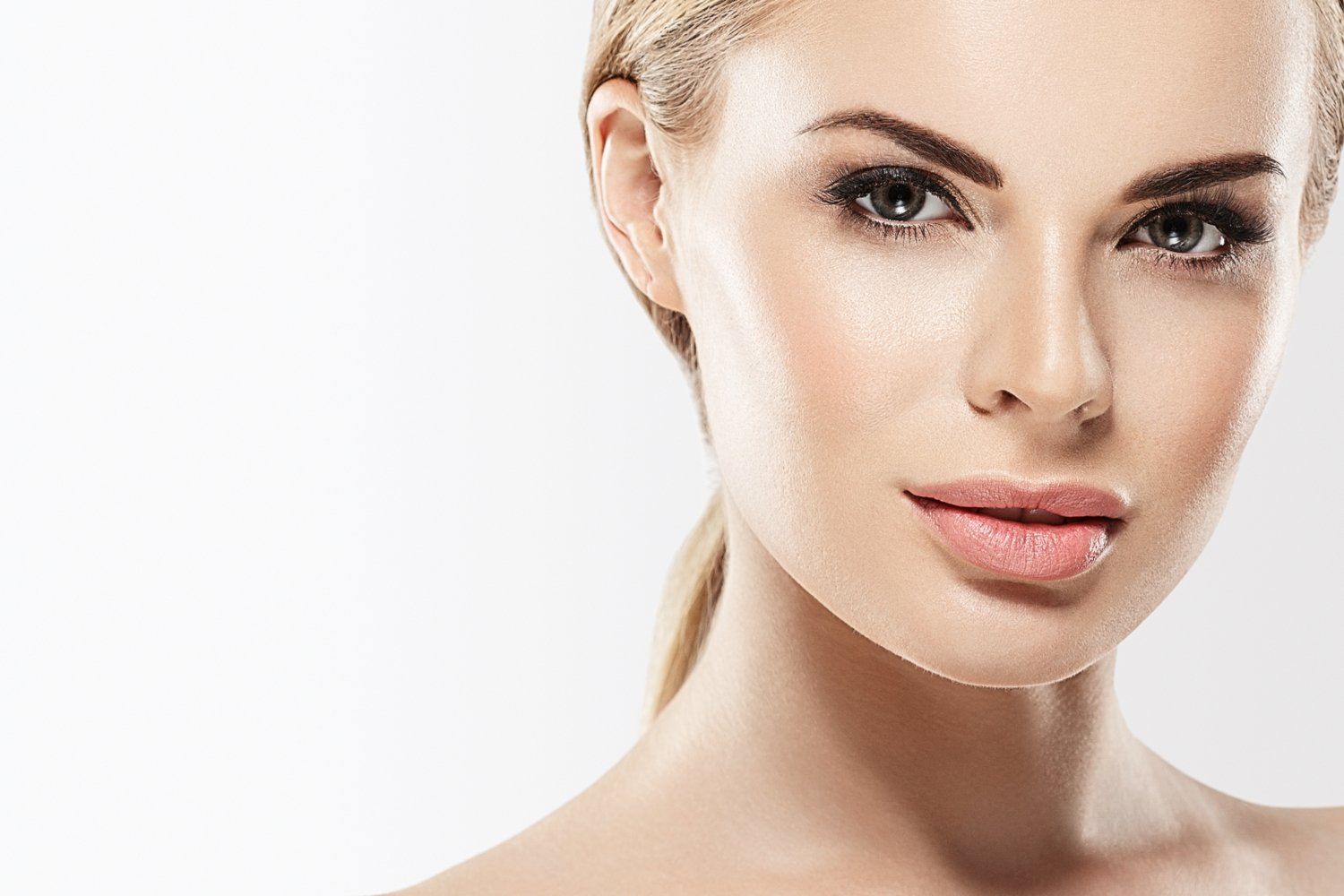 Un primer plano del rostro de una mujer con una cola de caballo sobre un fondo blanco.