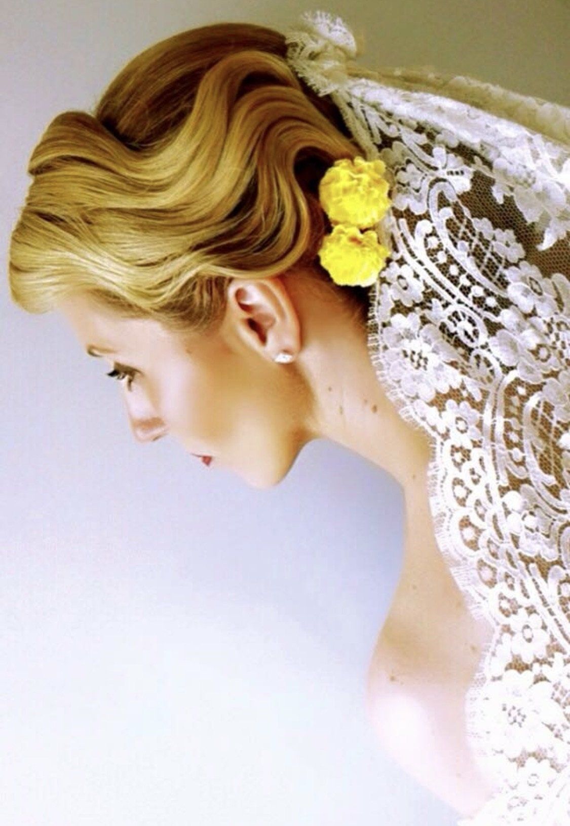 Una mujer que lleva un vestido de encaje blanco tiene flores amarillas en el pelo.
