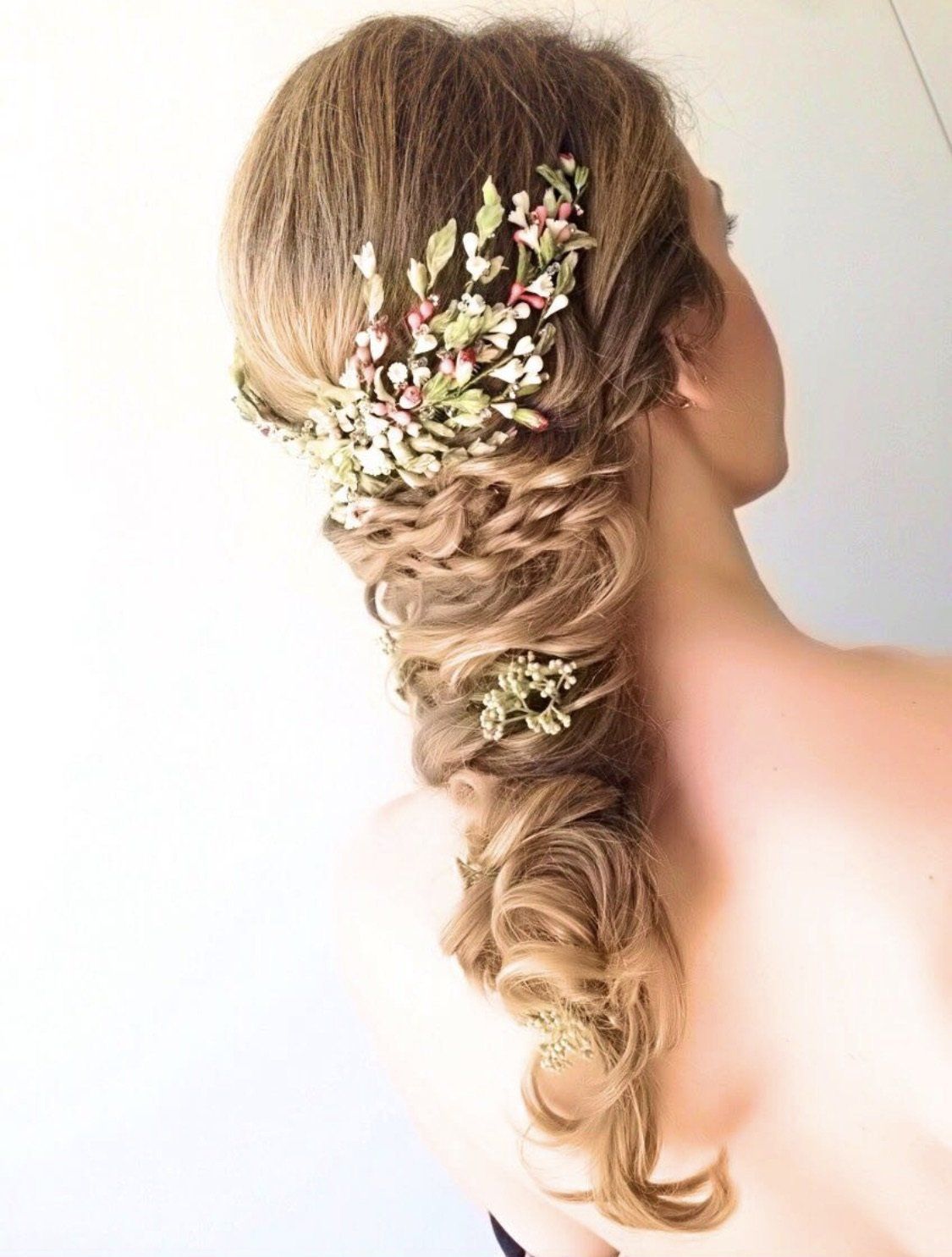 Una mujer lleva un peinado trenzado con flores en el cabello.