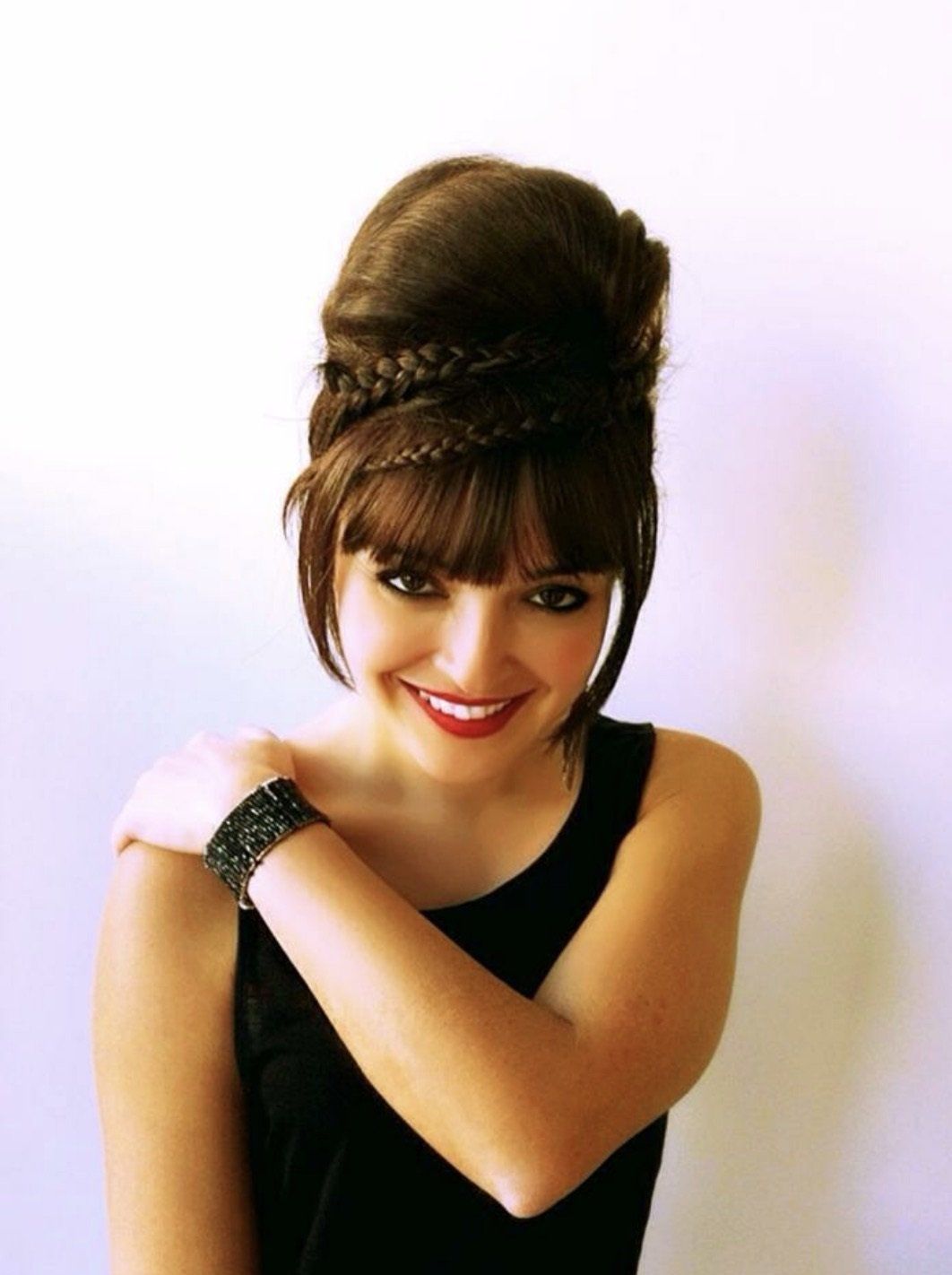 Una mujer que lleva una camiseta negra sin mangas tiene los brazos cruzados.