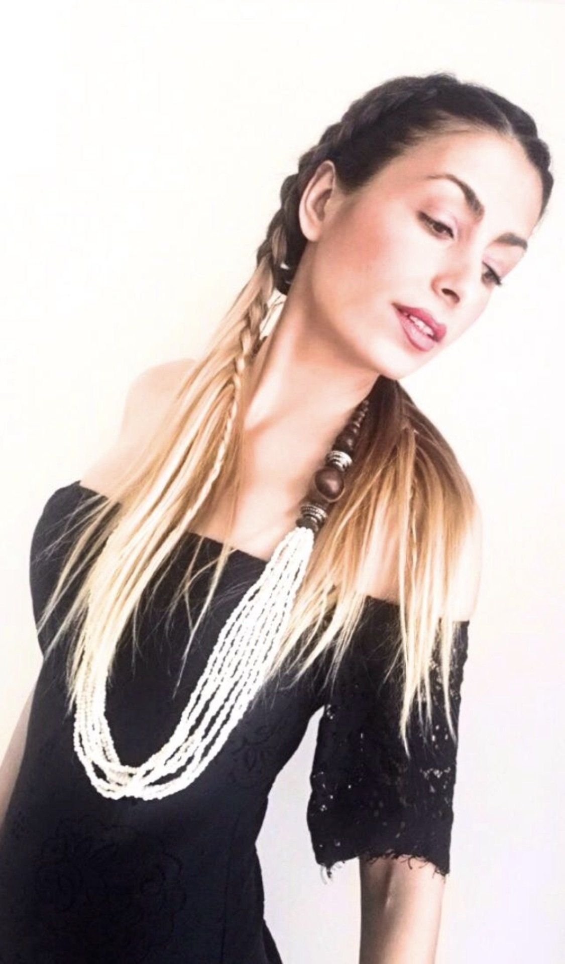 Una mujer que lleva un vestido negro y un collar de perlas.