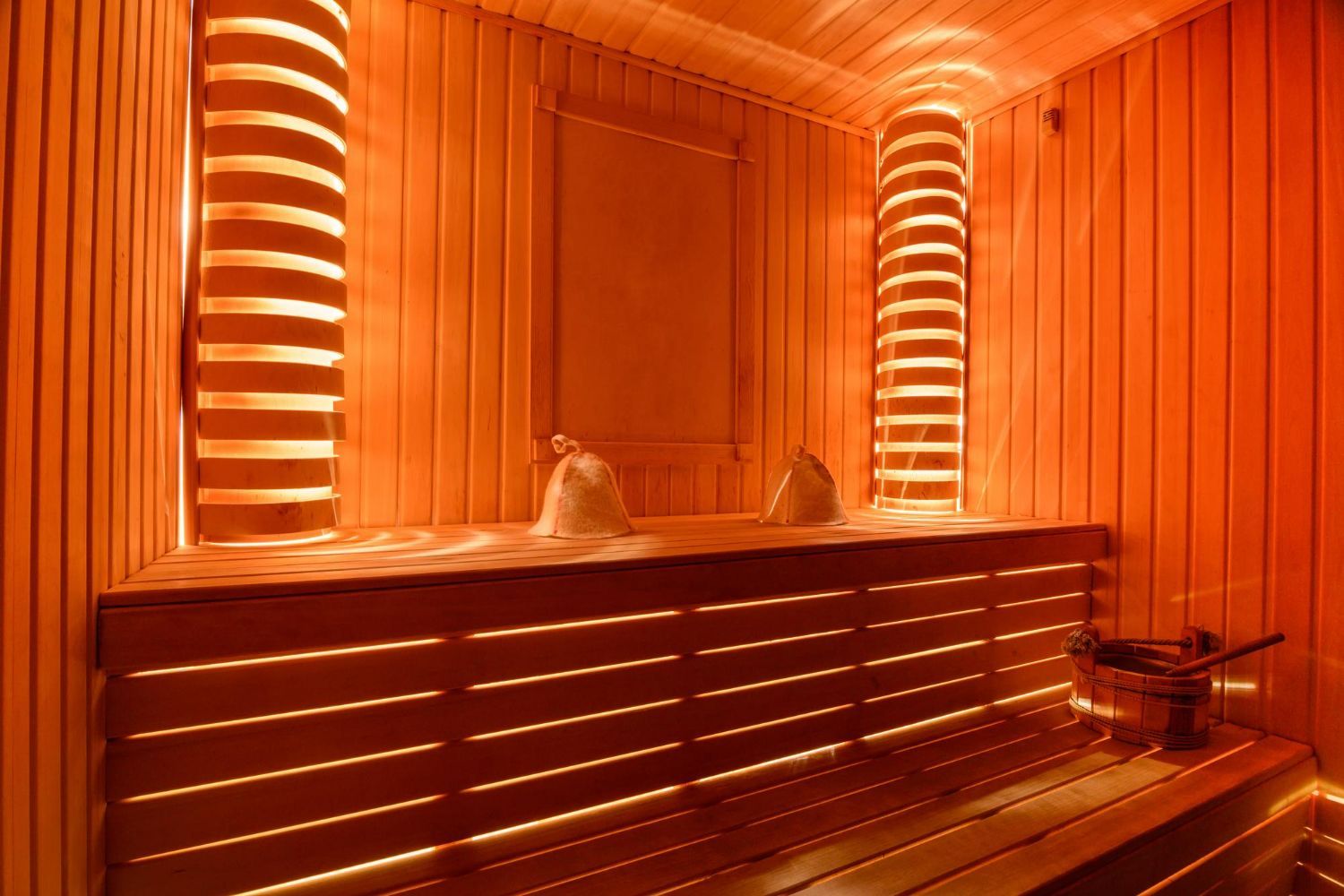 Wooden sauna interior with warm orange lighting.