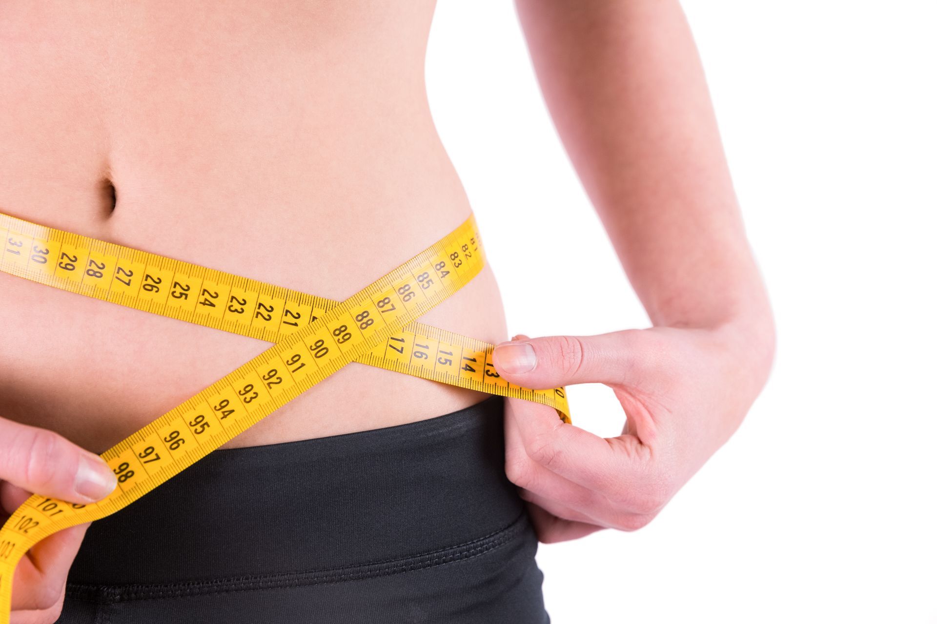 A woman is measuring her waist with a tape measure