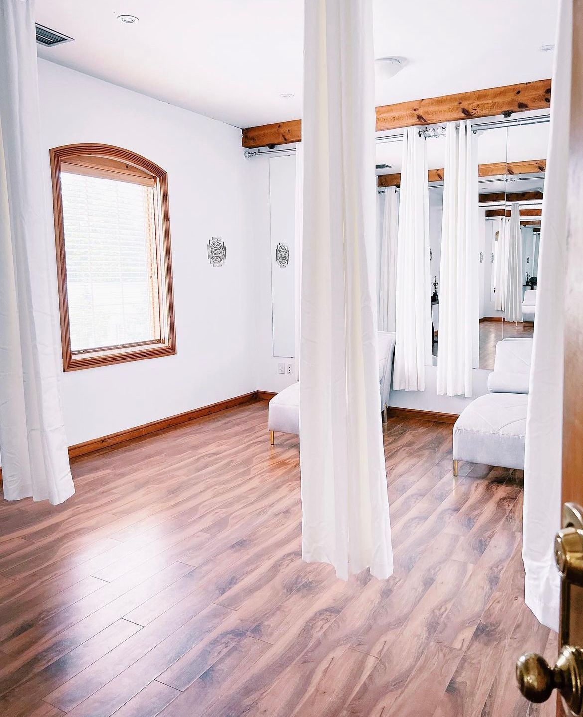 A room with hardwood floors and white curtains
