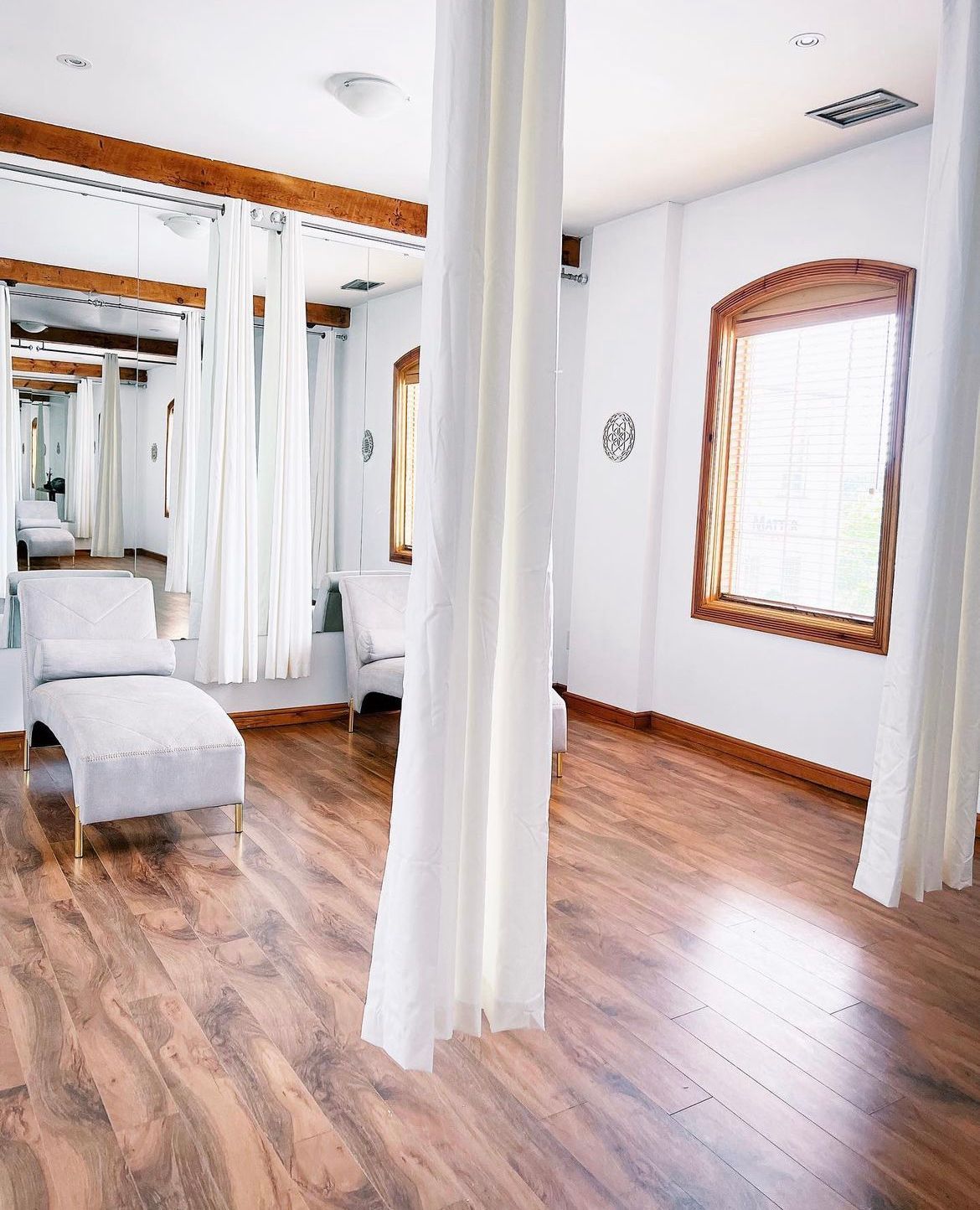 A living room with hardwood floors and white curtains