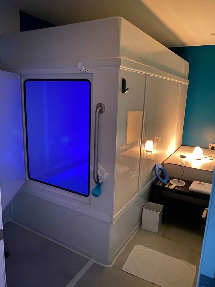 A room with a floating tank with a blue light on it.