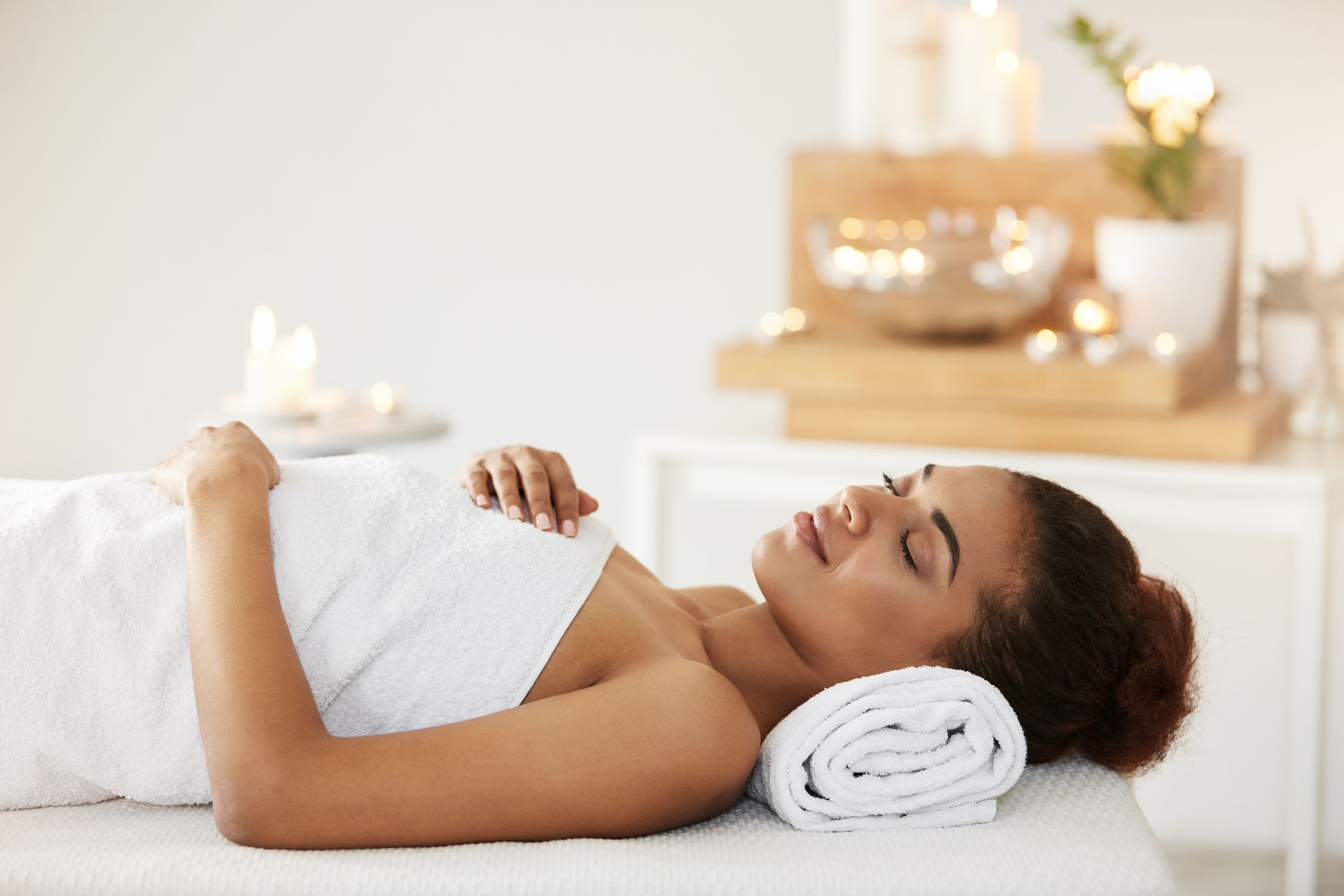 A woman is laying on a massage table wrapped in a towel.