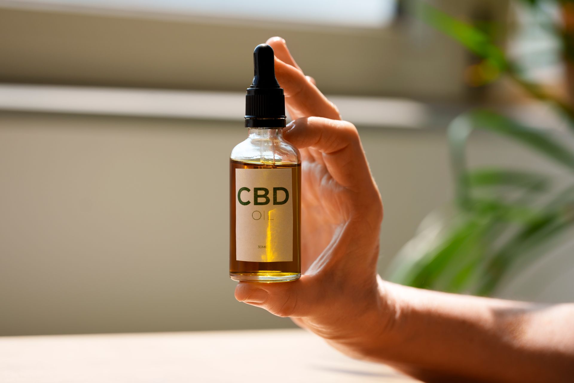 A person is holding a bottle of cbd oil in their hand.