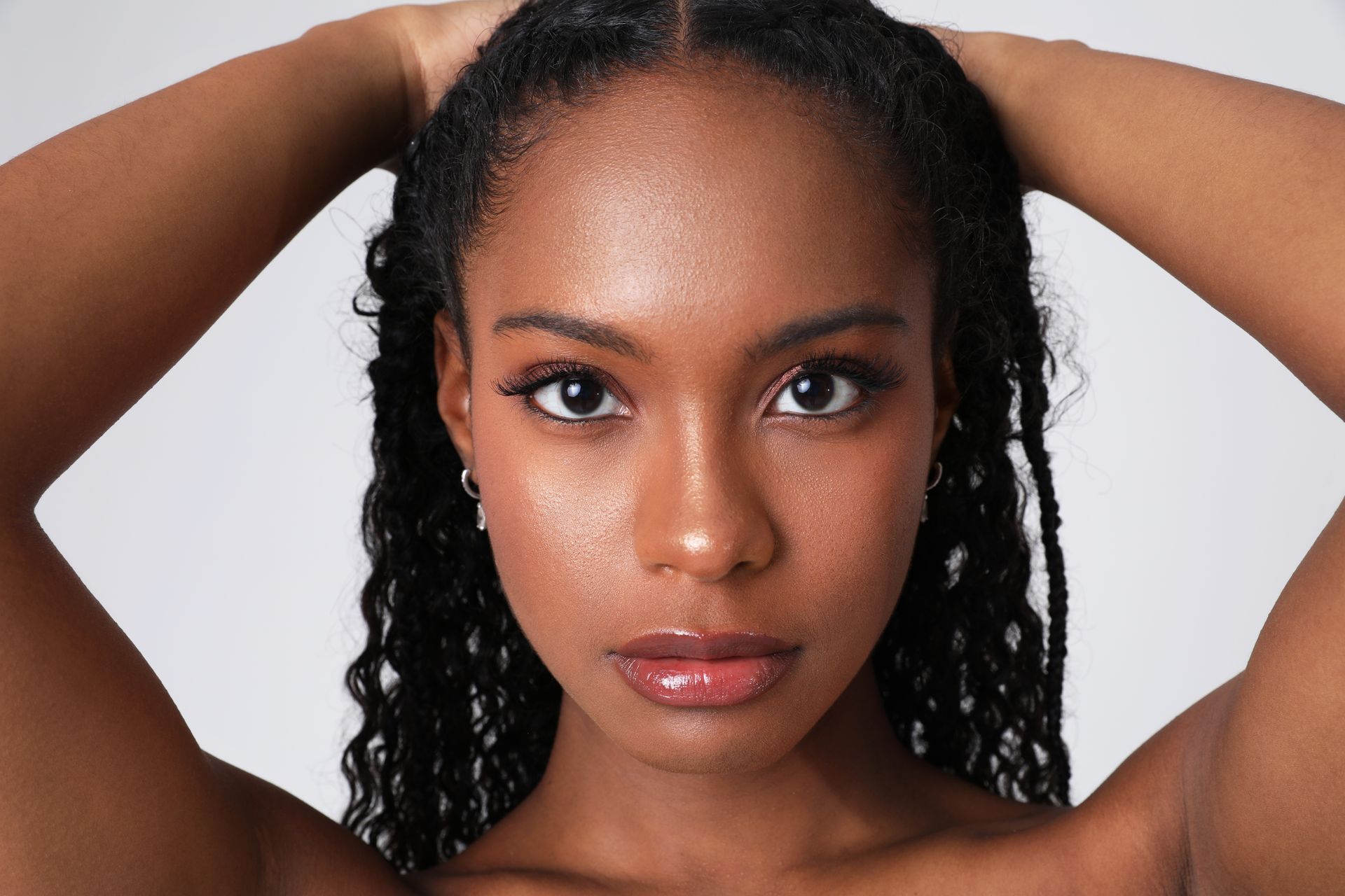 A close up of a woman 's face with her hands in her hair